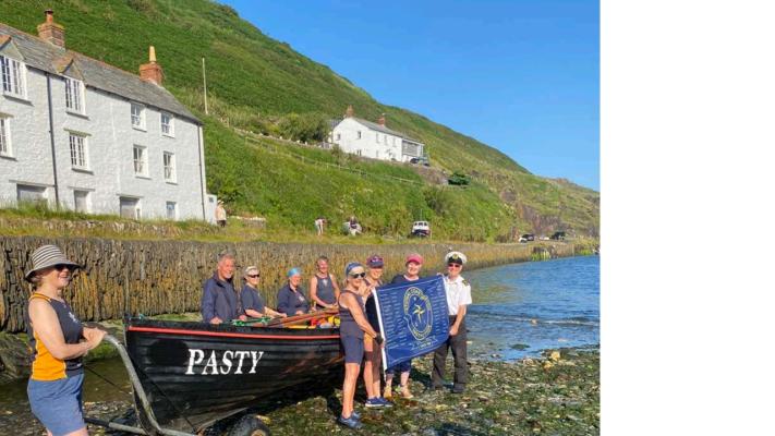The Anniversary flag is handed over to the Boscastle racing gig "Pasty" for the first leg of its journey to Padstow