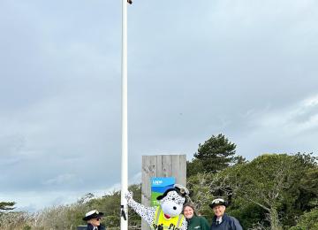 On NCI Awareness Day Station Mascot "Spot" hoists the NCI Flag 